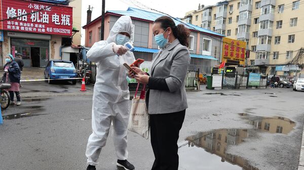 Медицинский работник измеряет температуру женщине в провинции Цзилинь, Китай