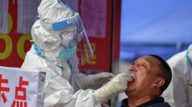 Медицинский работник делает тест на COVID-19 мужчине в провинции Цзилинь, Китай