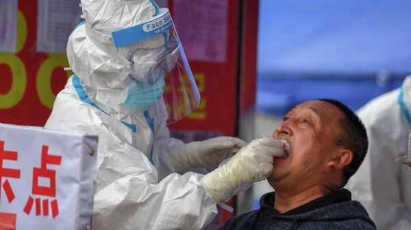 Медицинский работник делает тест на COVID-19 мужчине в Китае