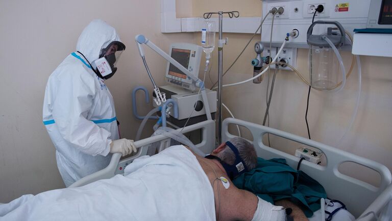 Медицинский работник возле кровати пациента в отделении реанимации и интенсивной терапии госпиталя COVID-19 в ГКБ No1 имени Н.И. Пирогова в Москве