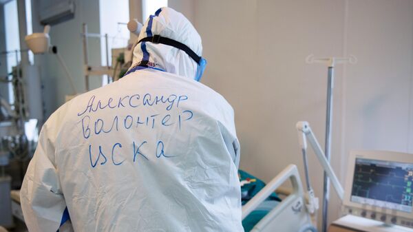 Волонтер возле кровати пациента в отделении реанимации и интенсивной терапии госпиталя COVID-19 в ГКБ No1 имени Н.И. Пирогова в Москве