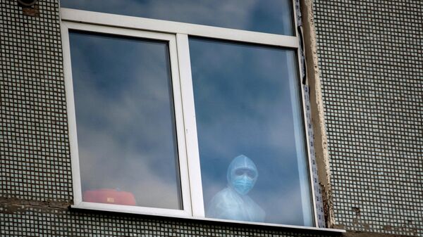 Медицинский работник в окне одной из палат Иркутской областной инфекционной больницы