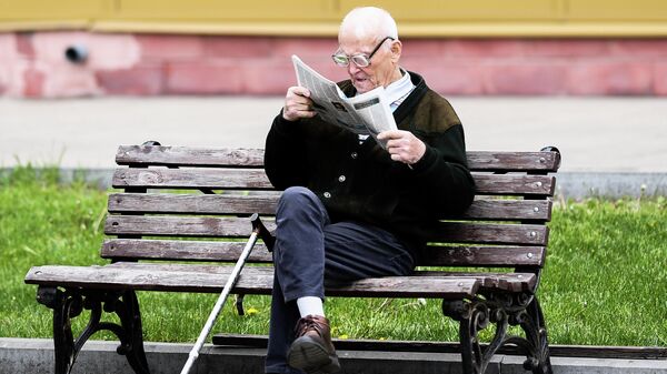 Мужчина читает газету на улице на лавочке