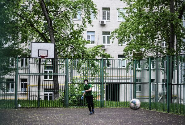 Подросток в защитной маске на спортивной площадке в одном из московских дворов во время режима самоизоляции жителей