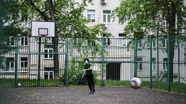 Подросток в защитной маске на спортивной площадке в одном из московских дворов во время режима самоизоляции жителей