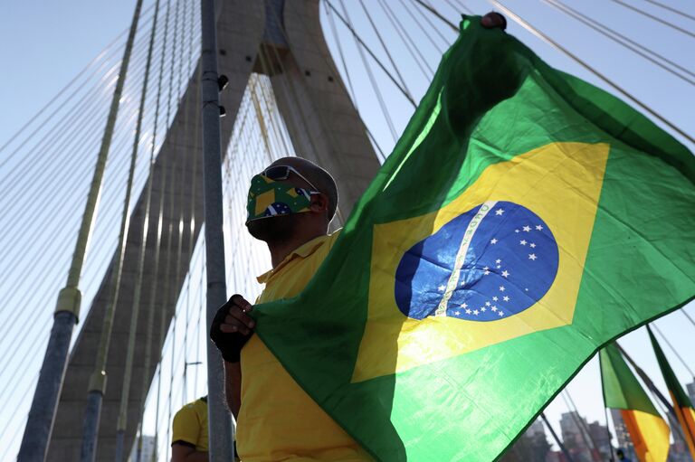 Сторонник президента Бразилии во время акции протеста против карантинных мер в Сан-Паулу Сторонник президента Бразилии во время акции протеста против карантинных мер в Сан-Паулу
