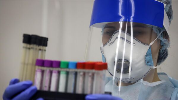 Медицинский работник держит в руках пробирки с биоматериалом для тестирования на наличие антител к коронавирусу