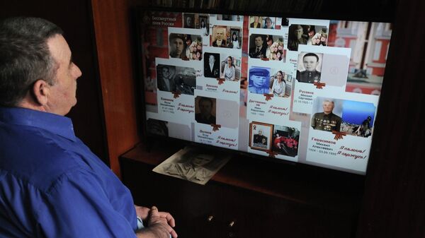 Мужчина смотрит онлайн-трансляцию акции Бессмертный полк