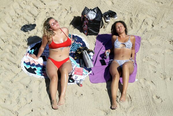 Девушки на пляже Каллеркоутс в Тайнмуте, Англия