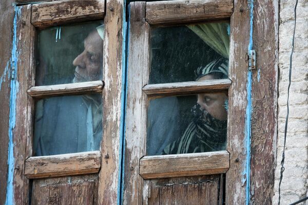 Местные жители выглядывают из окна своего дома в Шринагаре, Кашмир 