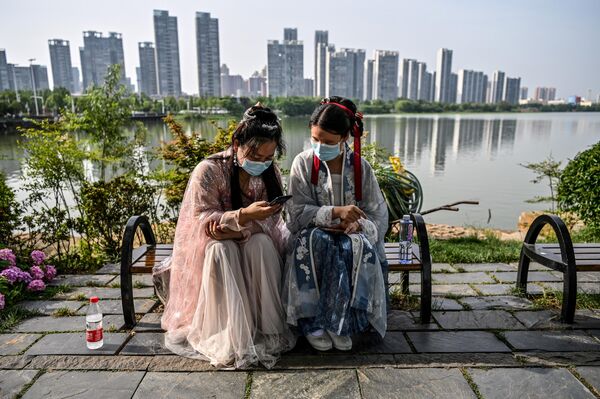 Девушки в масках и традиционных костюмах династий Сун и Тан в парке в Ухане, Хубэй