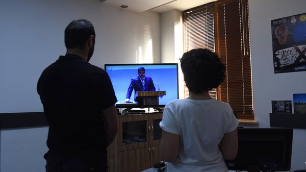 Мужчина и женщина смотрят трансляцию инаугурации избранного президента Нагорного Карабаха Араика Арутюняна