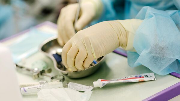 Врач-стоматолог в медицинских перчатках во время работы 