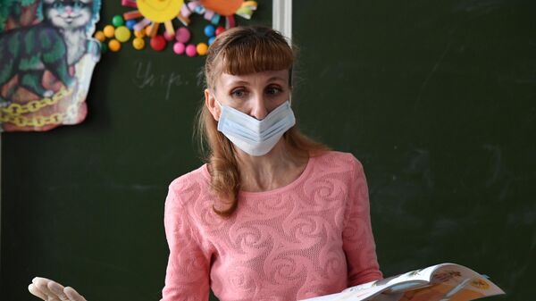 Учительница в защитной маске ведет урок  в общеобразовательной школе