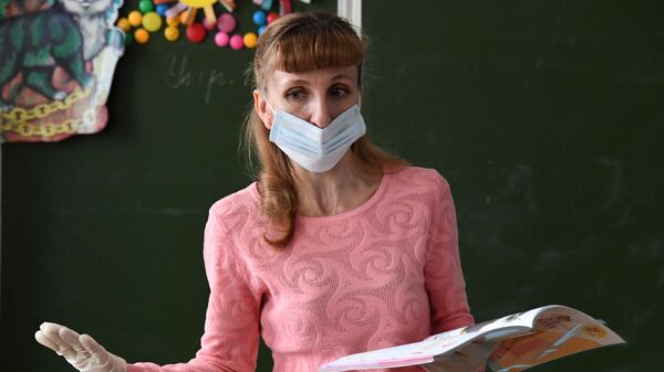 Учительница в защитной маске ведет урок  в общеобразовательной школе