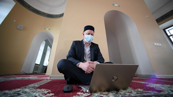 Верующий смотрит прямую трансляцию праздничного вагаза в Галеевской мечети в Казани