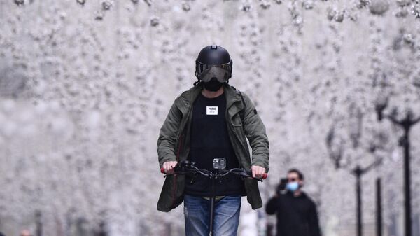 Мужчина в защитном шлеме катается на электросамокате по Никольской улице в Москве