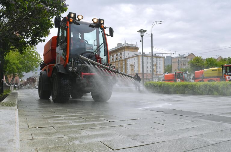 Автомобиль коммунальных служб во время дезинфекции тротуаров в Москве