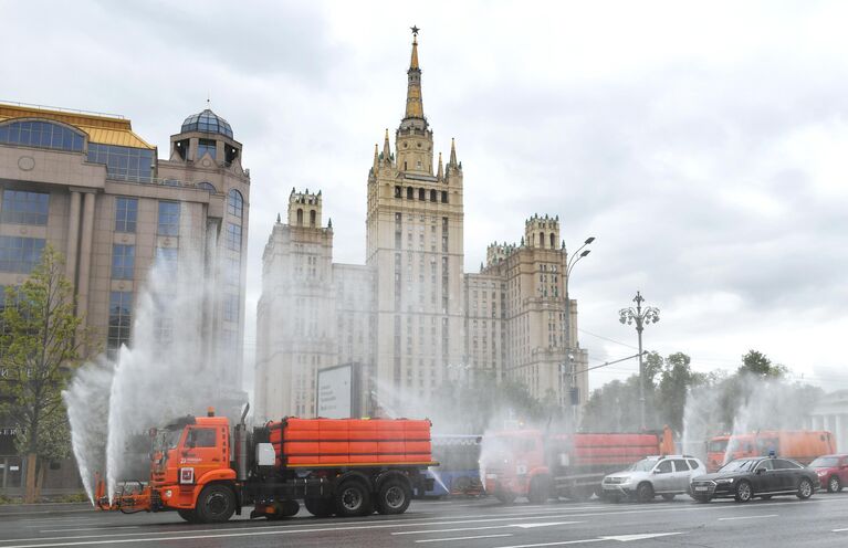 Автомобили коммунальных служб во время дезинфекции проезжей части дорог в Москве