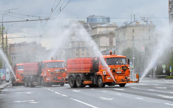 Автомобили коммунальных служб во время дезинфекции проезжей части дорог в Москве