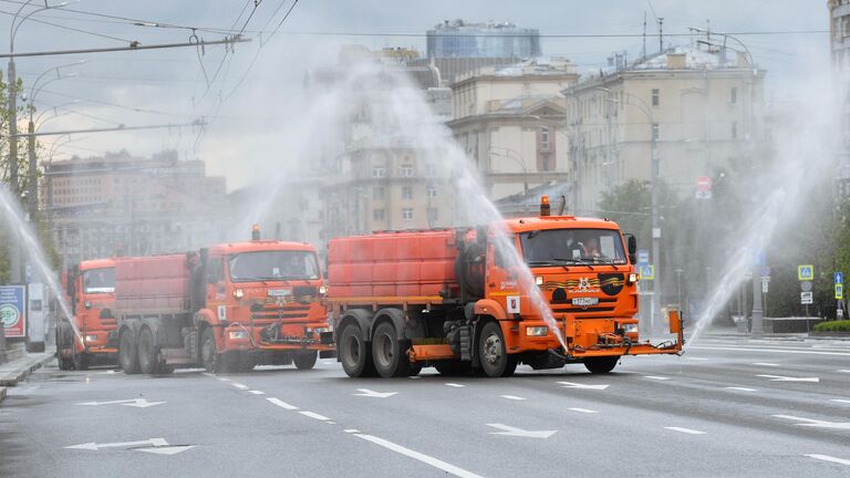 Автомобили коммунальных служб во время дезинфекции проезжей части дорог в Москве