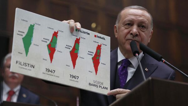 Президент Турции Реджеп Тайип Эрдоган держит плакат, на котором изображены территории Палестины