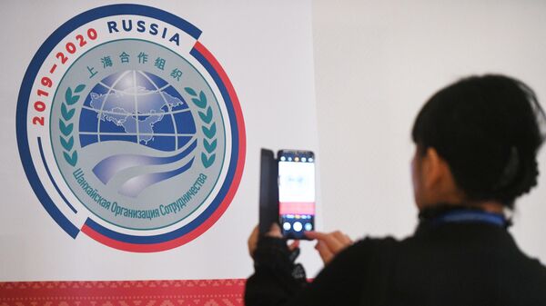 Участница совещания руководителей министерств и ведомств науки и техники государств-членов ШОС фотографирует логотип председательства России в ШОС