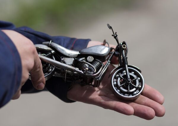 Мастер Станислав Черновасиленко держит миниатюрную копию модели мотоцикла Harley-Davidson Street 750