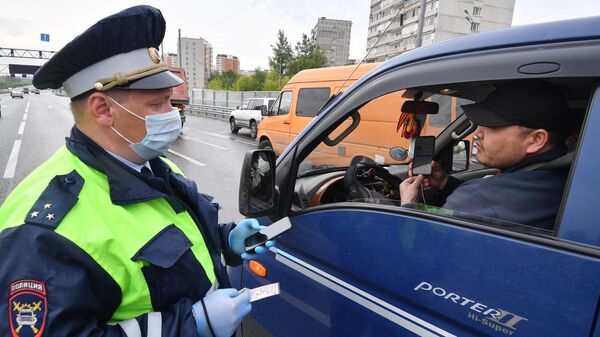 Инспектор ДПС проверяет цифровой пропуск у водителя