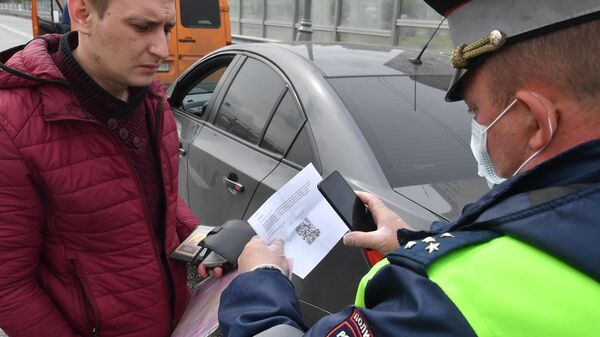 Инспектор ДПС проверяет цифровой пропуск у водителя