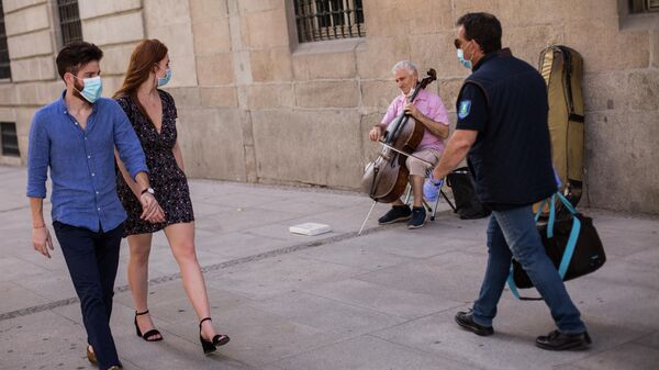 Прохожие и уличный музыкант на одной из улиц Мадрида