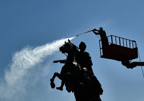 Сотрудник коммунальной службы моет памятник Петру I на Сенатской площади в Санкт-Петербурге