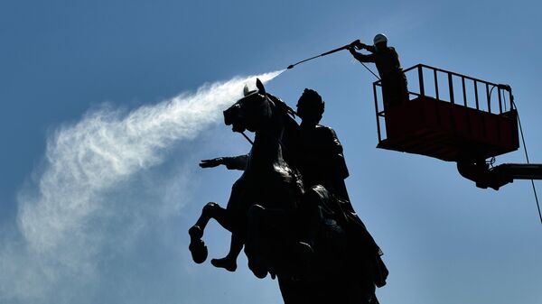 Сотрудник коммунальной службы моет памятник Петру I на Сенатской площади в Санкт-Петербурге