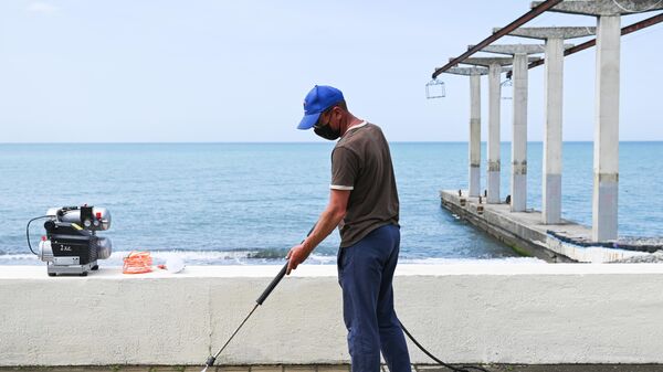 Мужчина моет набережную пляжа Чайка-1 в Сочи
