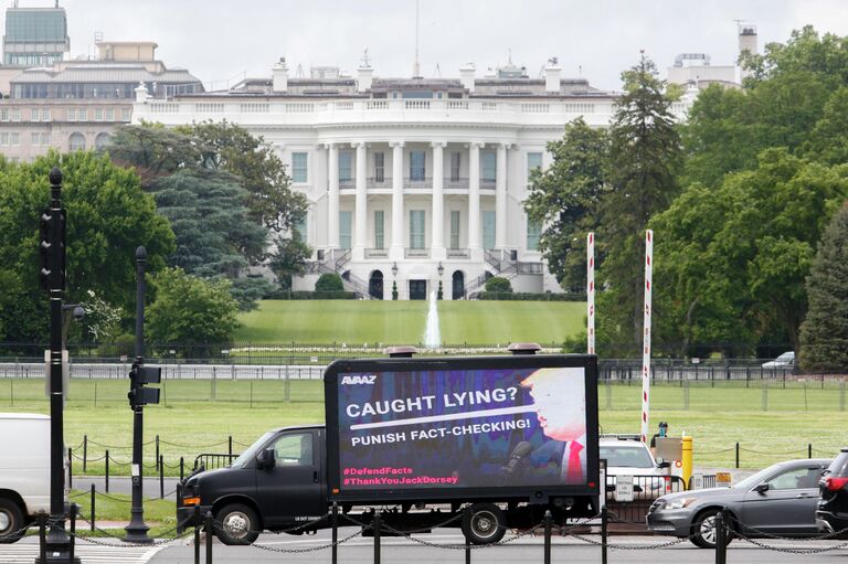 Рекламный щит с изображением президента США Дональда Трампа перед Белым домом