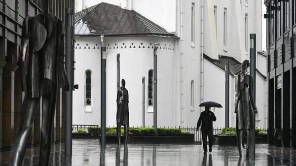 Прохожий во время дождя на пешеходной площади бизнес-центра Белая Площадь в Москве