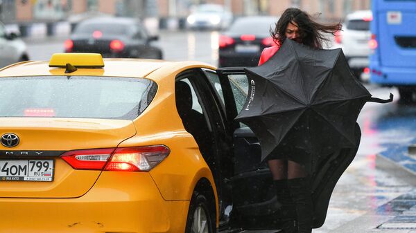 Девушка садится в такси во время дождя