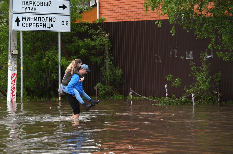 Мужчина переносит девушку через лужу в поселке Опалиха Московской области