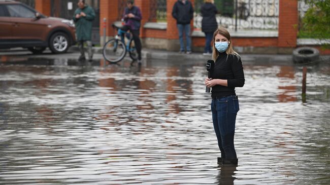 Корреспондент готовится к репортажу на затопленной улице в поселке Опалиха Московской области