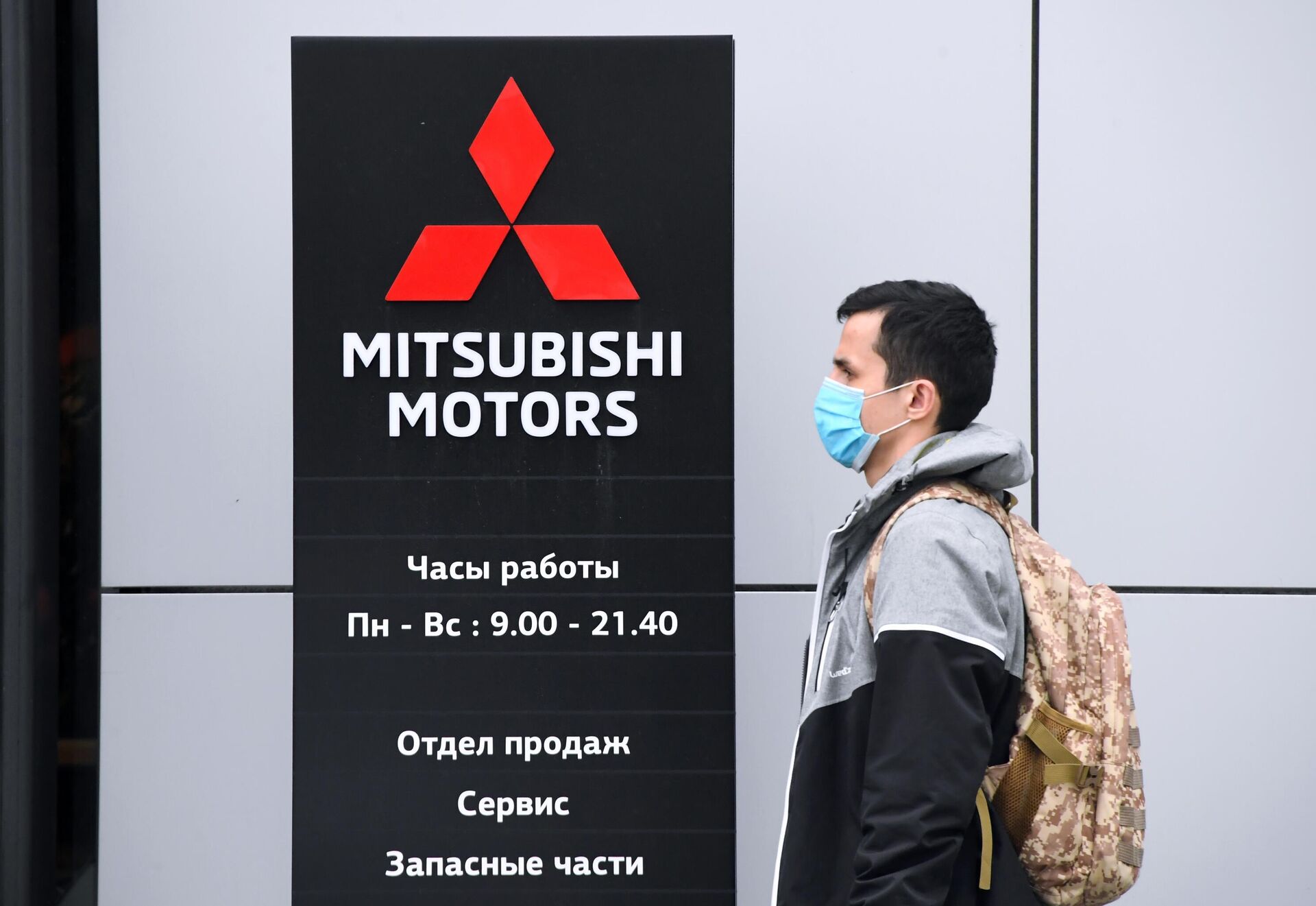 Прохожий в медицинской маске у автомобильного салона Mitsubishi Motors в Москве - РИА Новости, 1920, 10.03.2022