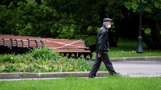 Мужчина в защитной маске гуляет в Центральном парке культуры и отдыха имени Горького, который вновь открылся для посещений в рамках второго этапа снятия ограничений в Москве