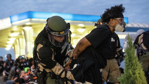 Сотрудник полиции задерживает участницу протеста в Миннеаполисе