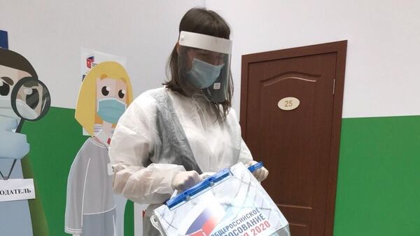 Девушка в защитном костюме члена участковой избирательной комиссии для проведения голосования по поправкам в Конституцию РФ
