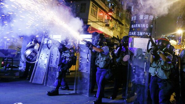 Сотрудники полиции во время пускают слезоточивый газ во время протестов в Гонконге 