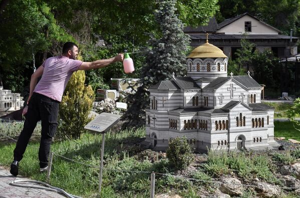 Мужчина у макета Владимирского собора в Херсонесе в Бахчисарайском парке Крым в миниатюре на ладони