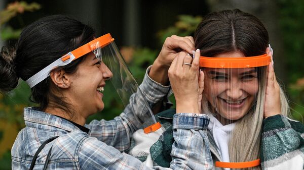 Девушки надевают пластиковые экраны для лица