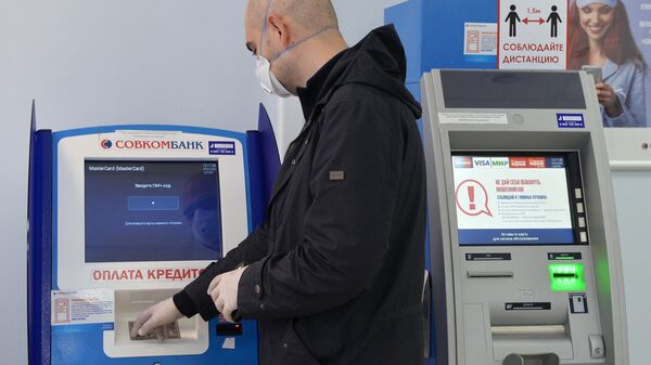 Клиент у терминала в отделении банка Совкомбанк в Москве