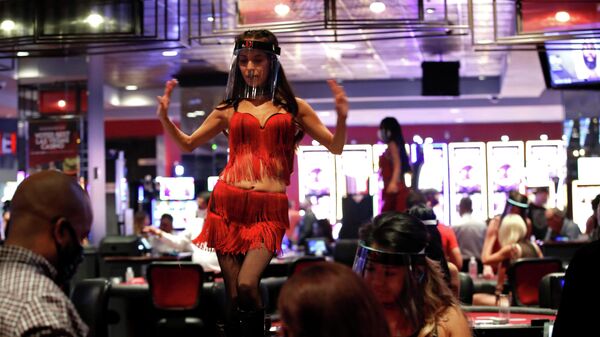 Женщина в защитной маске танцует на столе в отеле-казино Лас-Вегаса