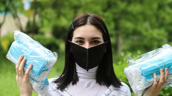 Волонтер держит в руках медицинские маски