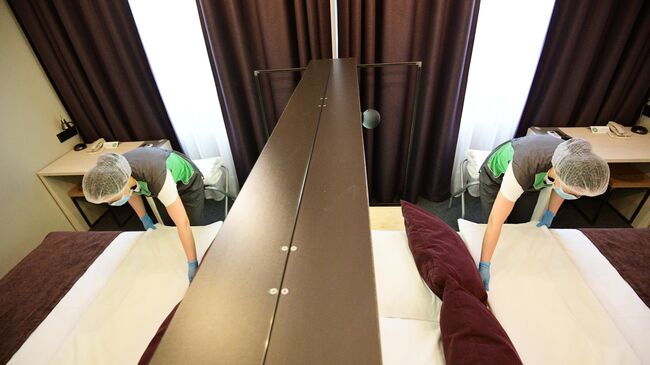 Горничная застилает кровать в номере отеля